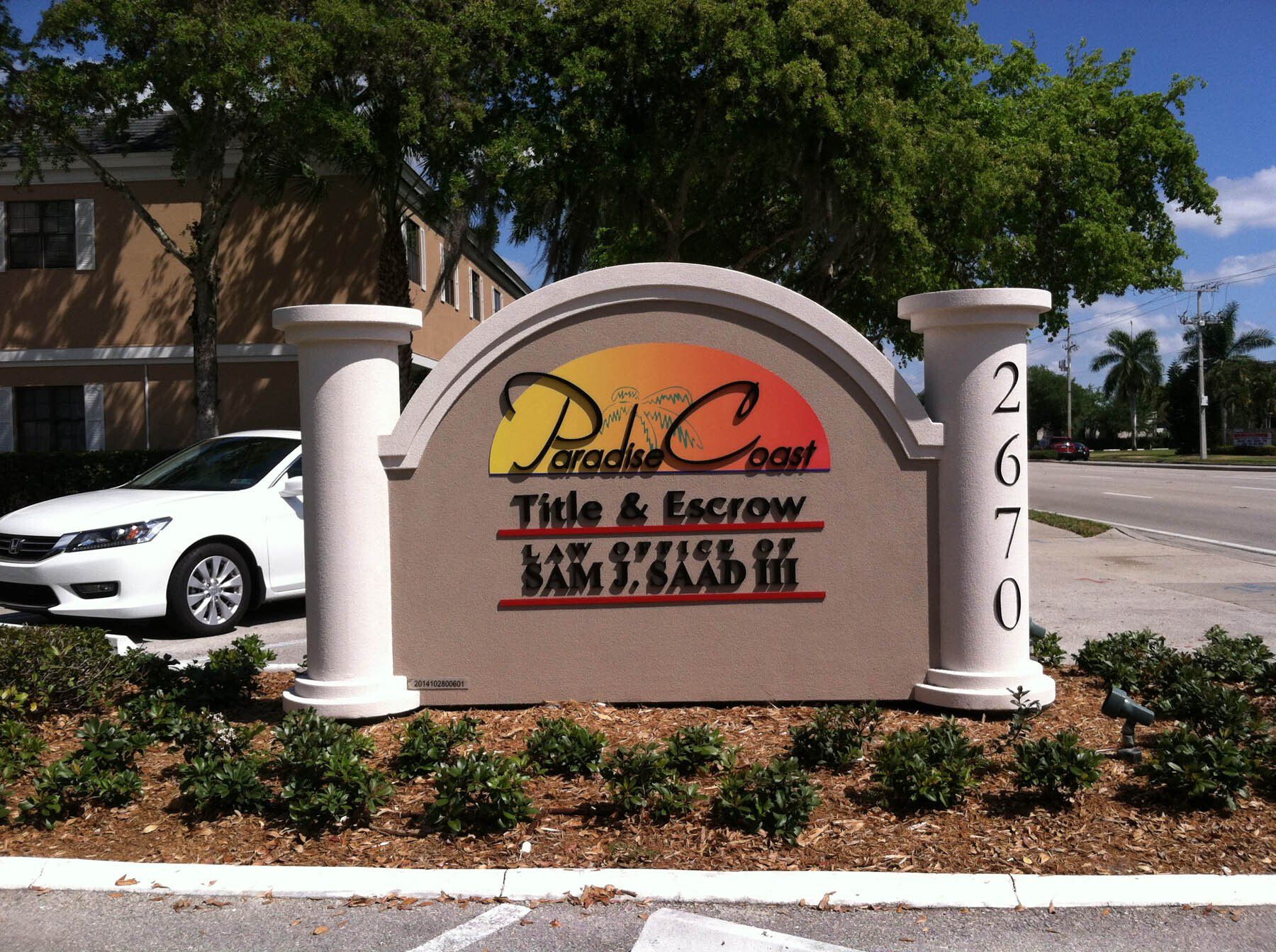 A white car is parked in front of a paradise coast title & escrow sign