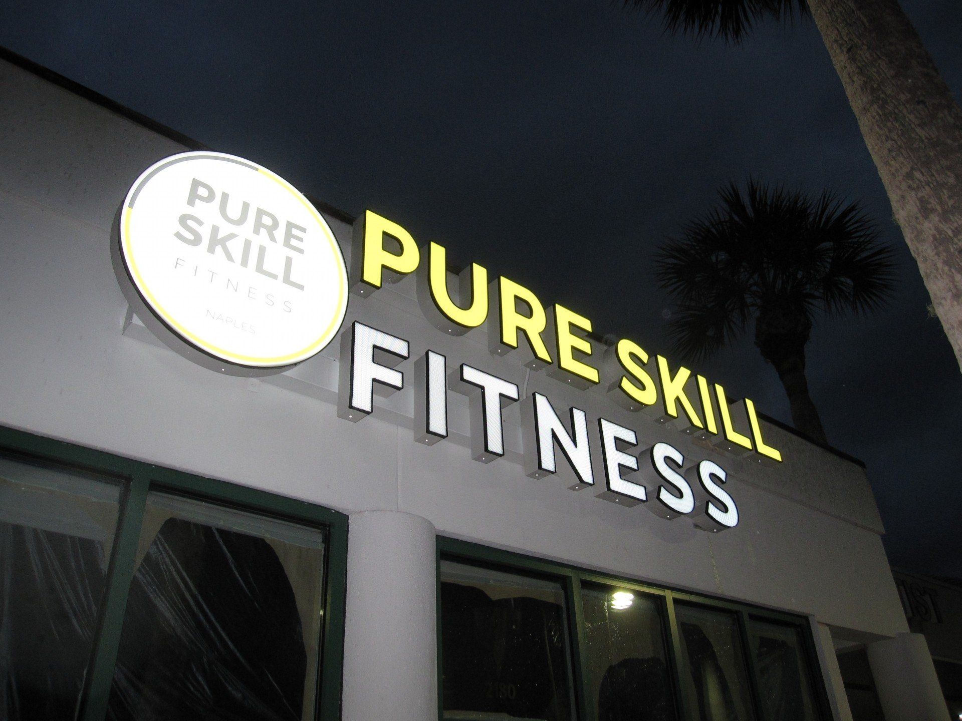 A sign for pure skill fitness is lit up at night