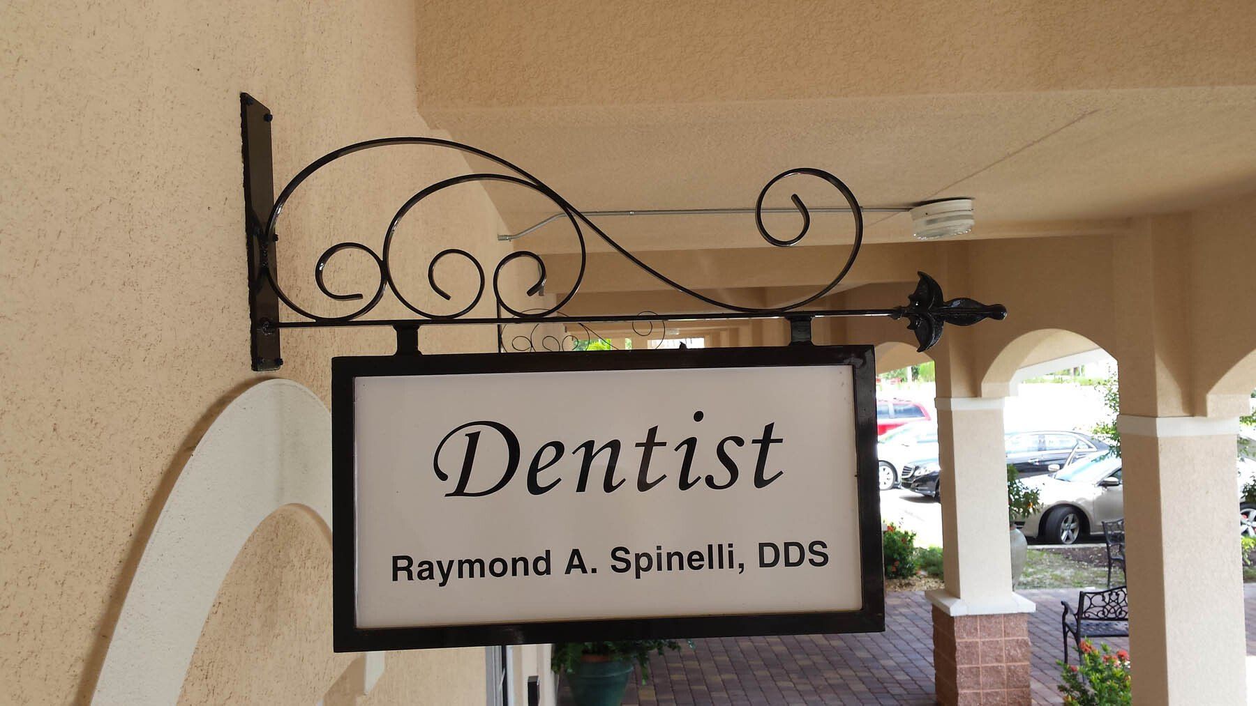 A dentist sign hangs from the side of a building