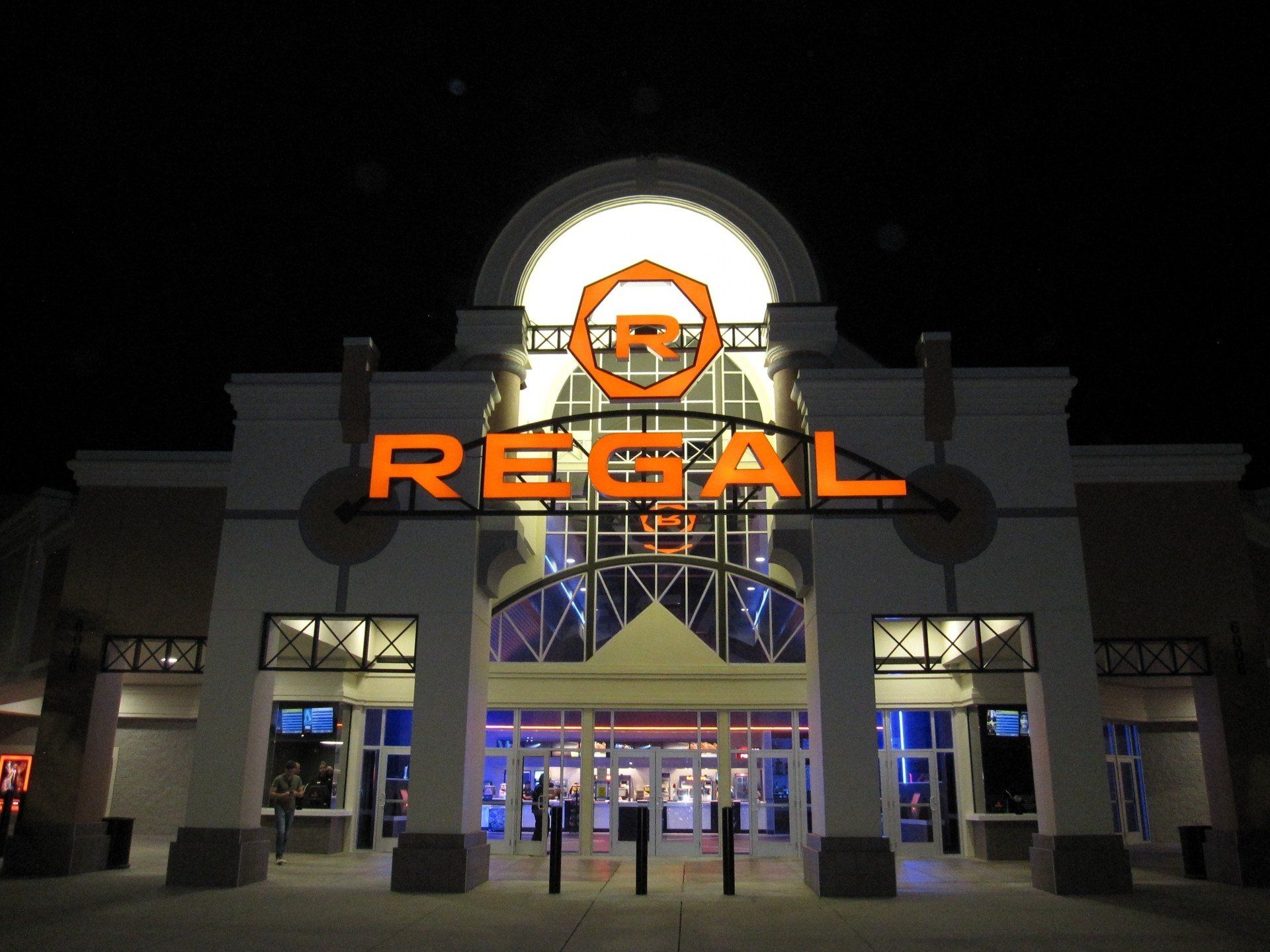 A regal movie theater is lit up at night