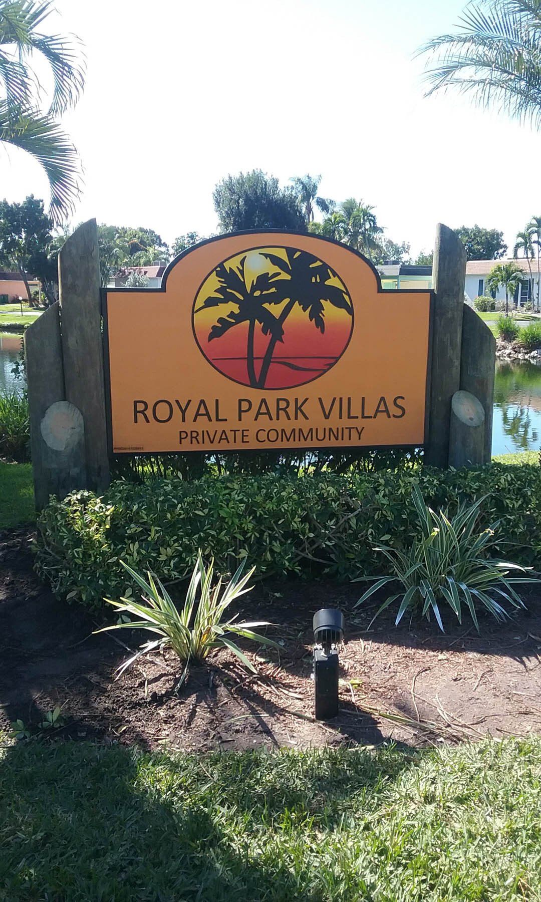A sign for royal park villas is in the middle of a lush green field.