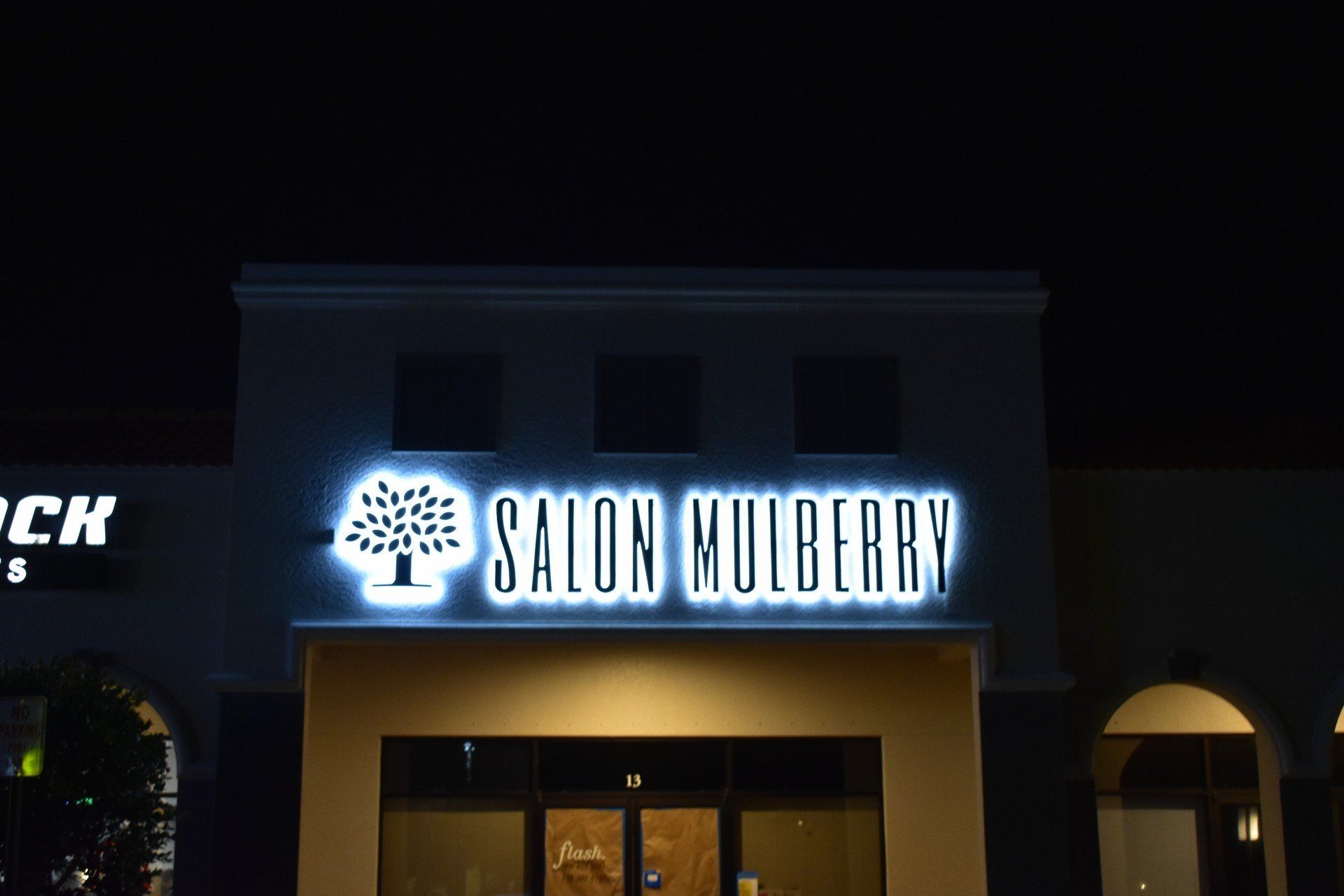A salon mulberry sign is lit up at night