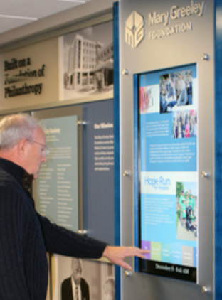 A man is pointing at a mary greeley foundation sign