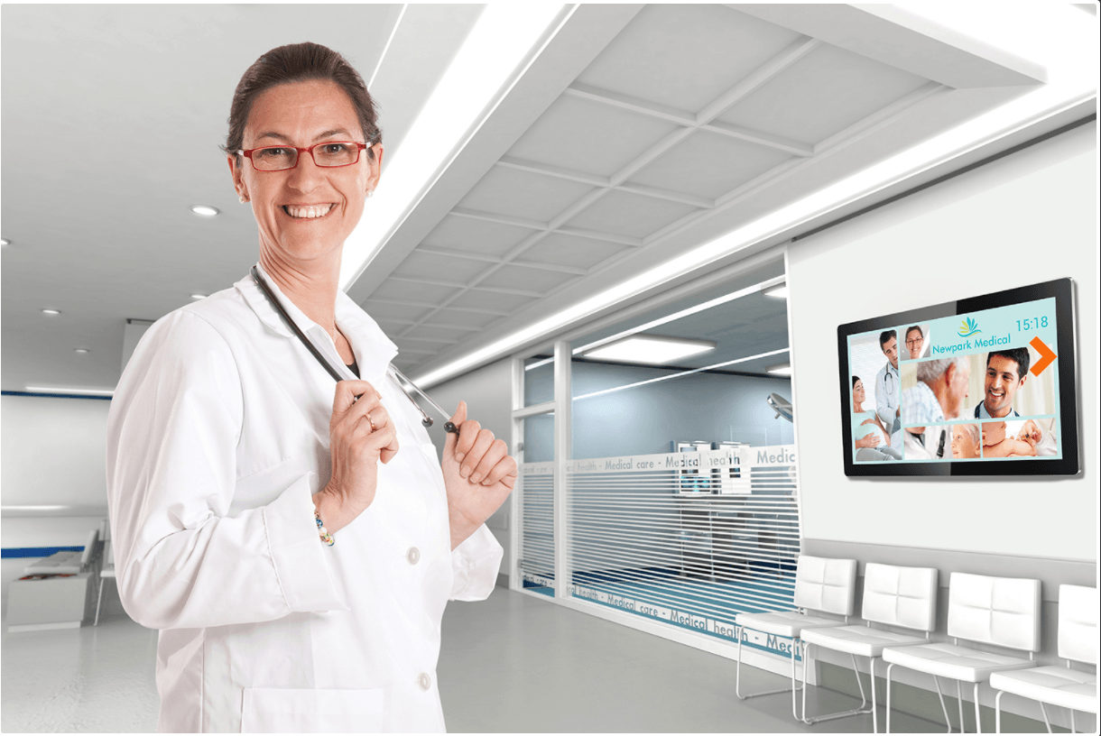 A female doctor is standing in a hospital hallway holding a stethoscope.