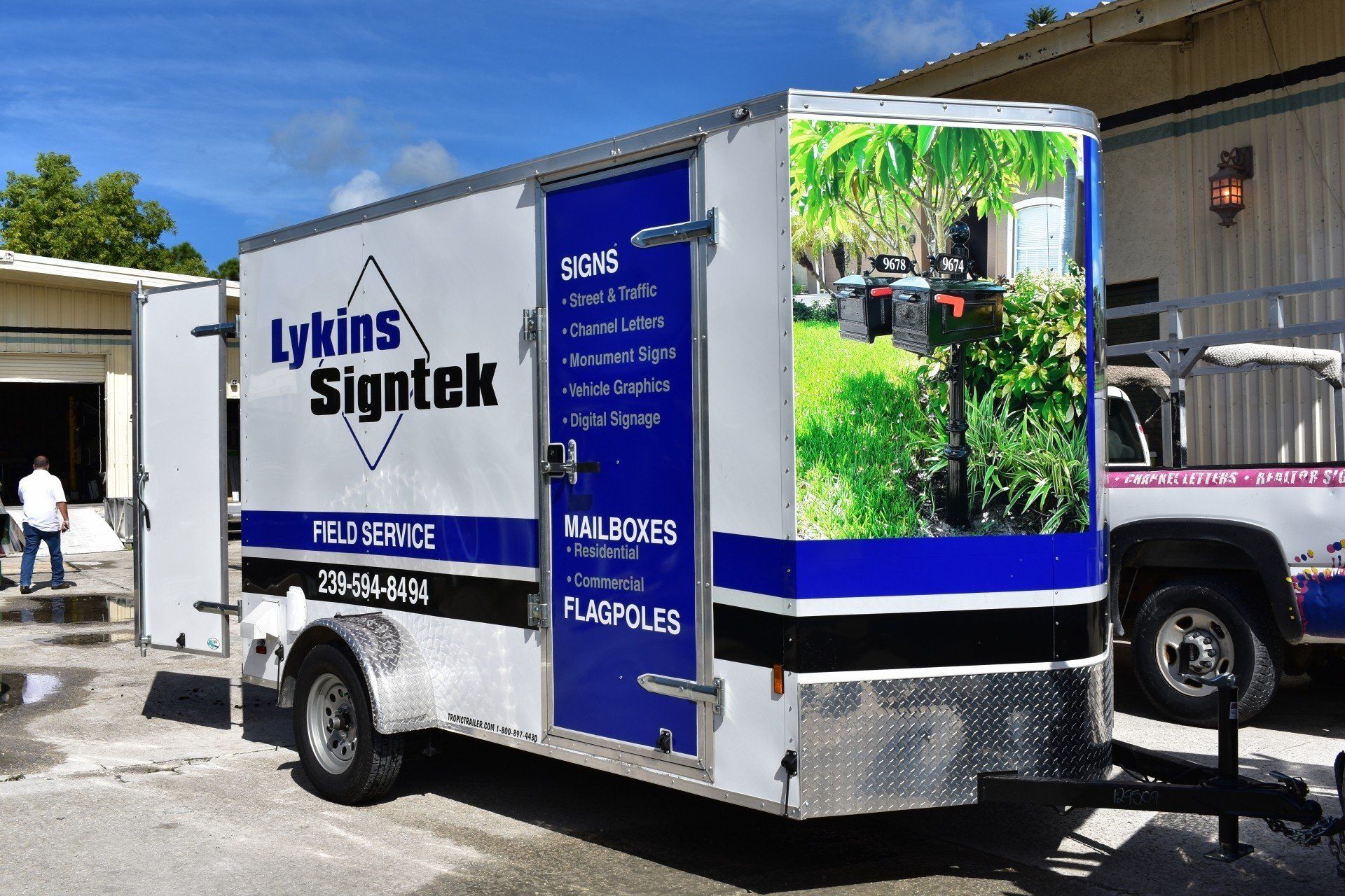 A trailer for lykins signtek is parked in front of a building