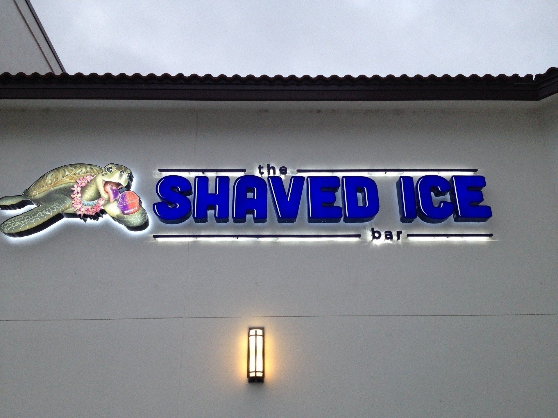 A sign for the shaved ice bar with a turtle on it