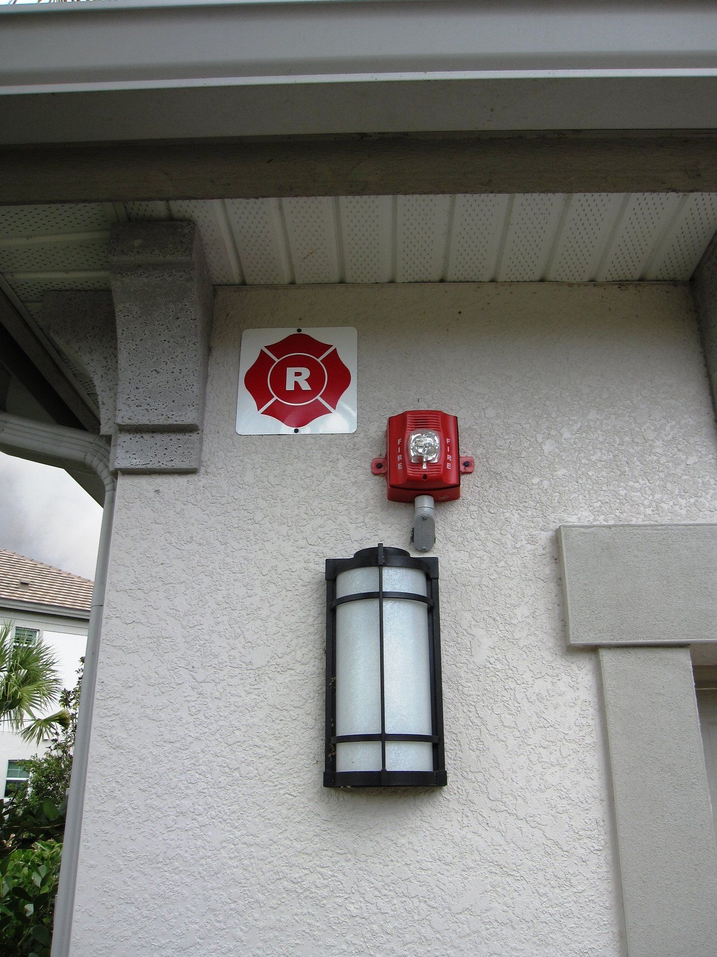 A red fire alarm is mounted on the side of a building