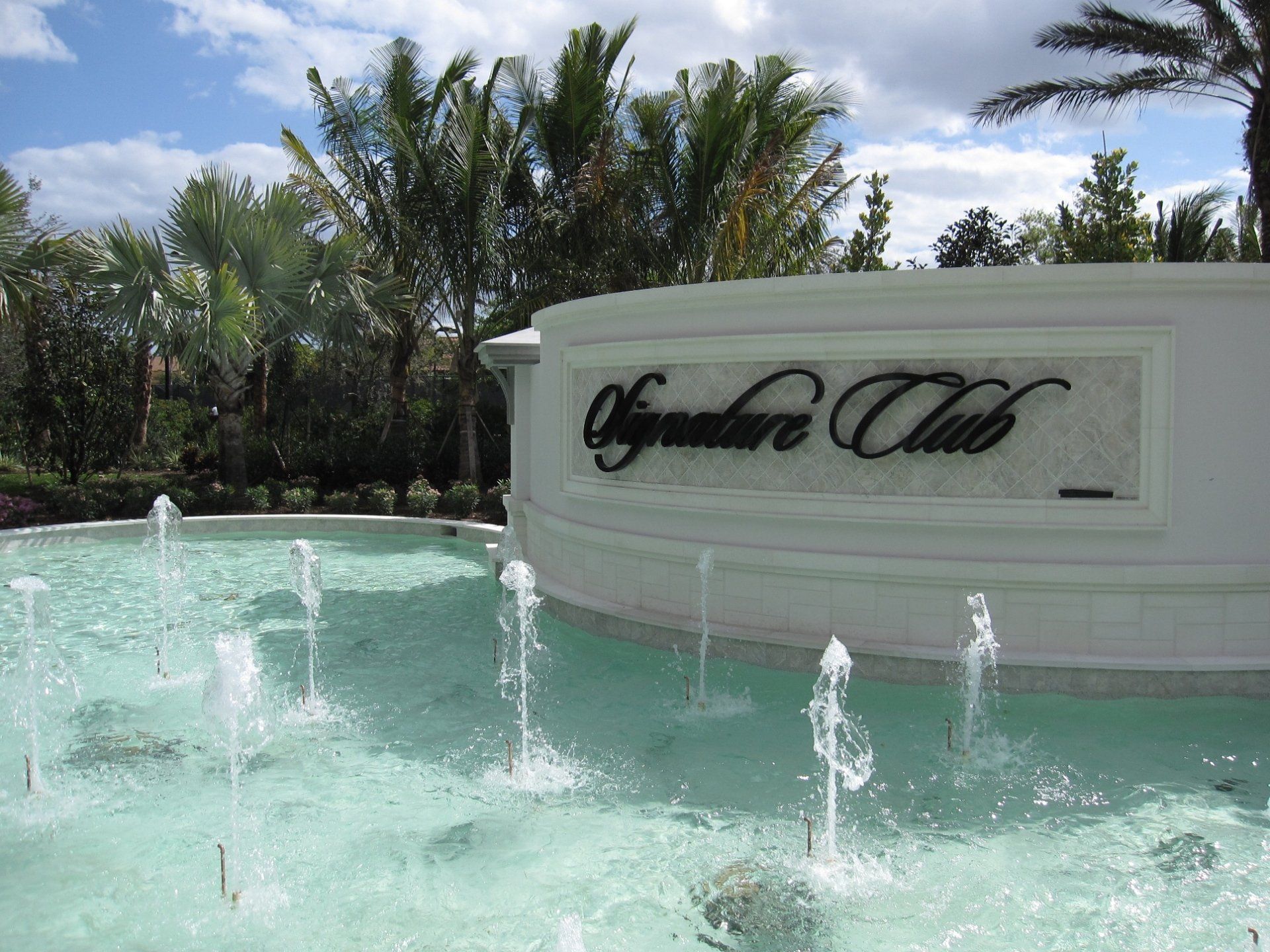 A fountain in front of a sign that says signature club