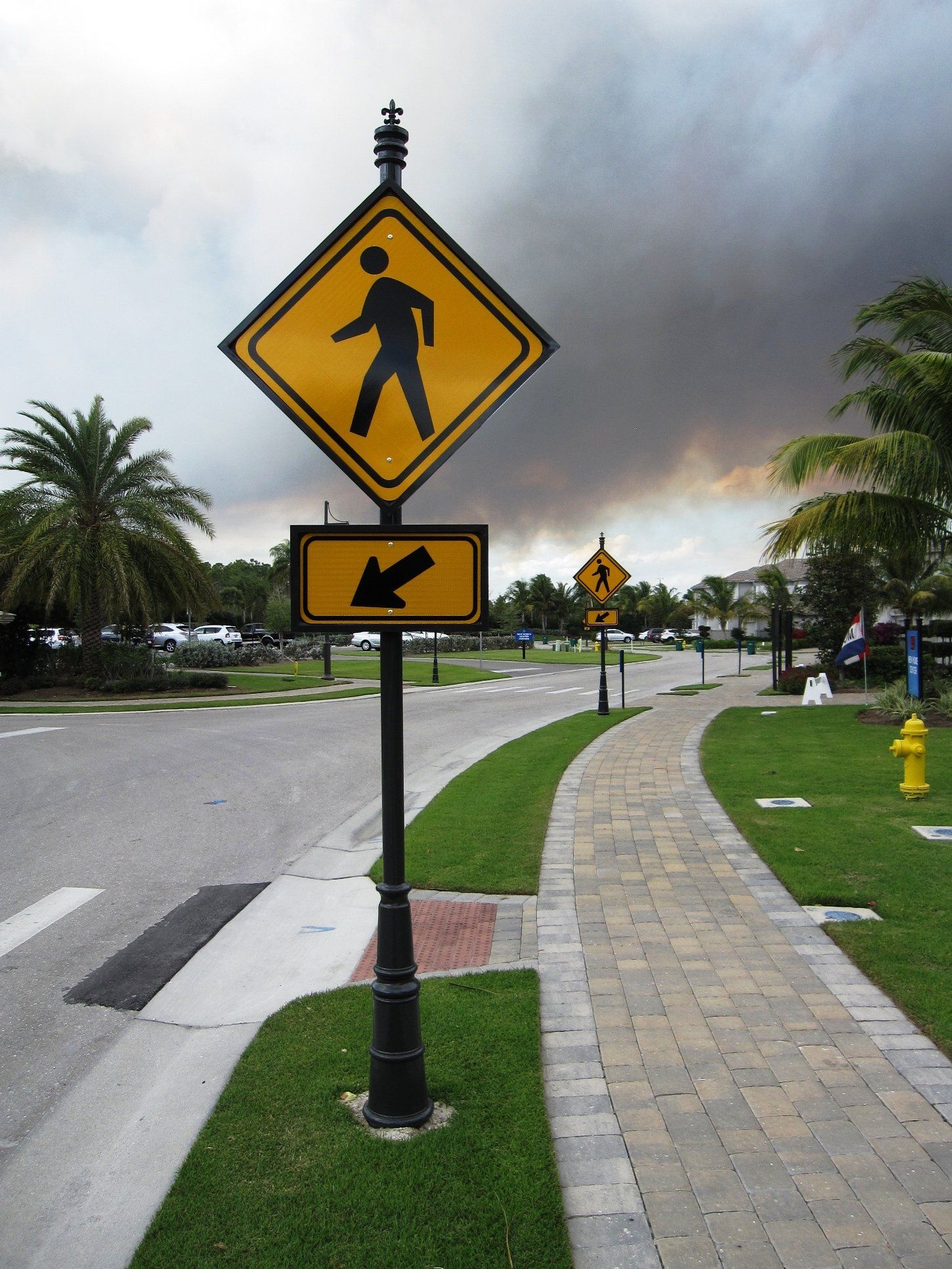 A pedestrian crossing sign with an arrow pointing to the left