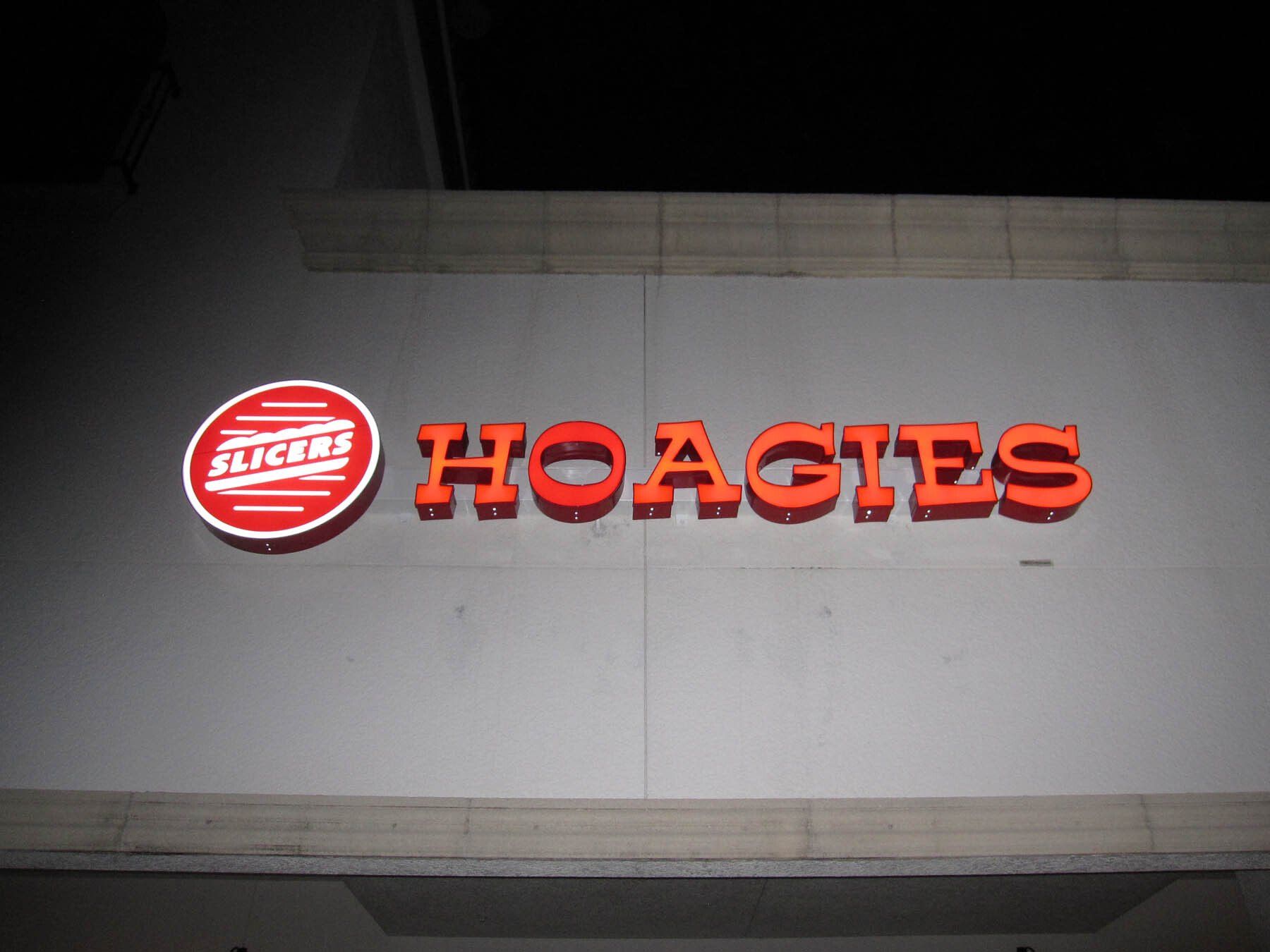 A hoagies sign is lit up at night