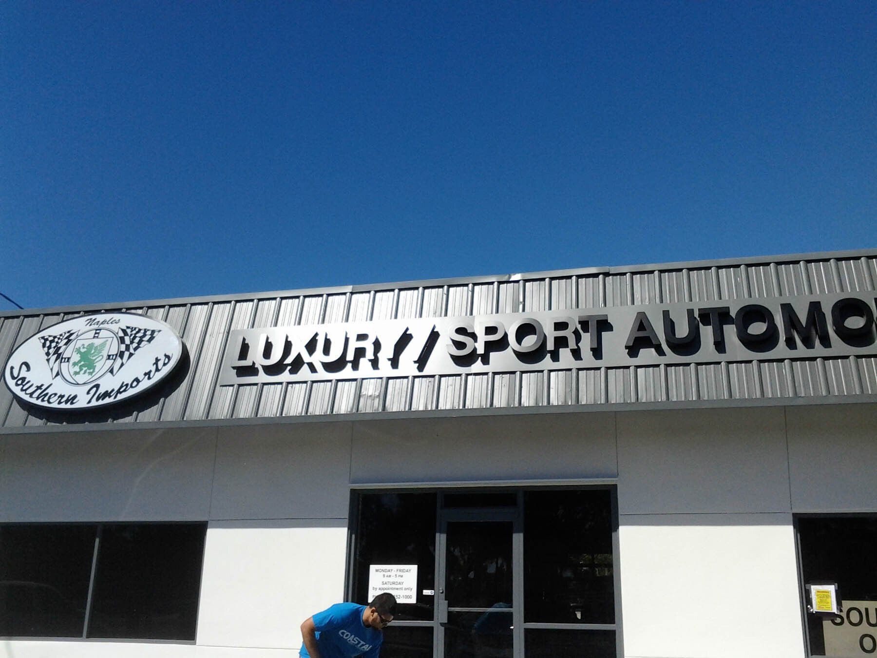 A man is standing in front of a building that says luxury sport automo