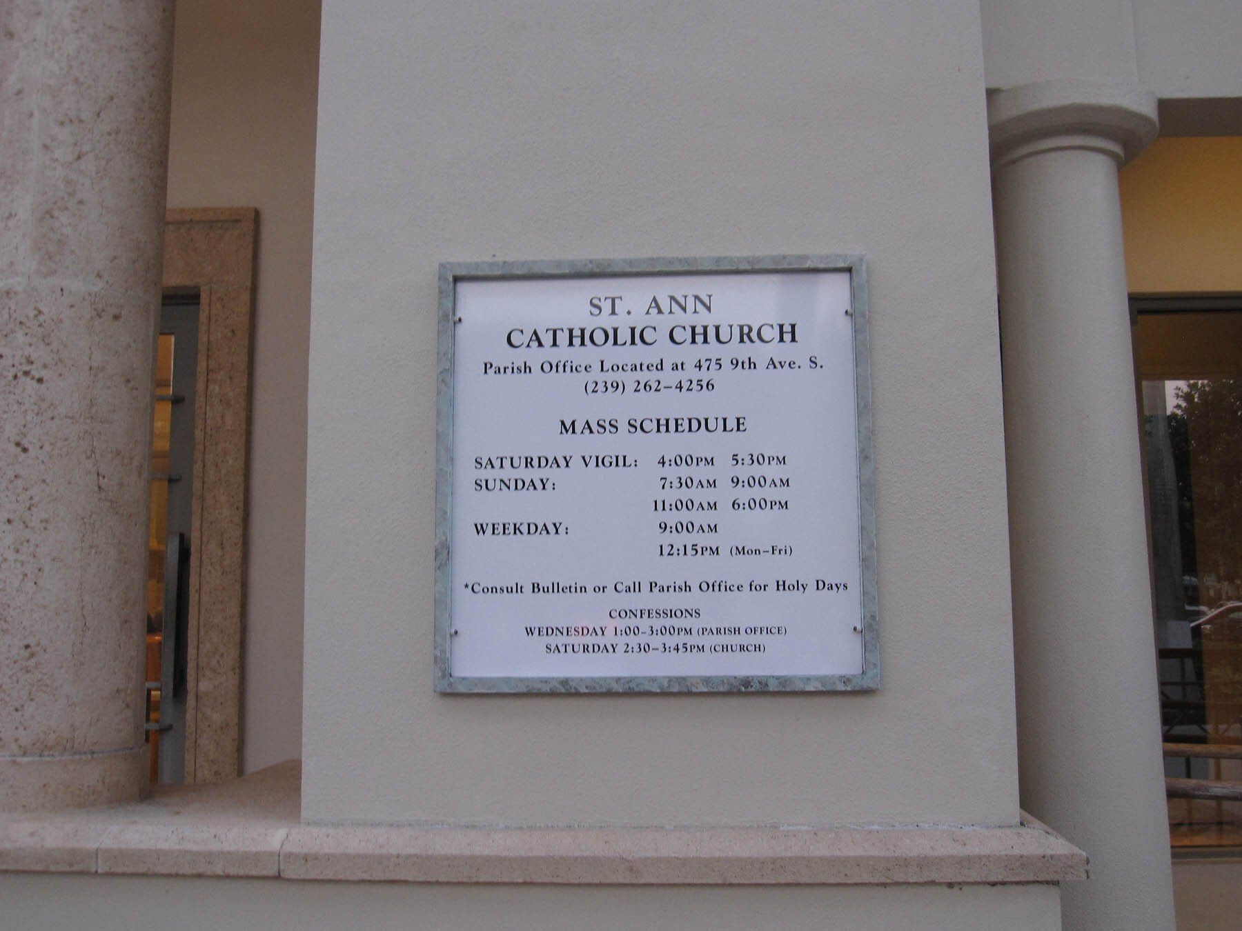 A sign for st. ann catholic church on a white wall