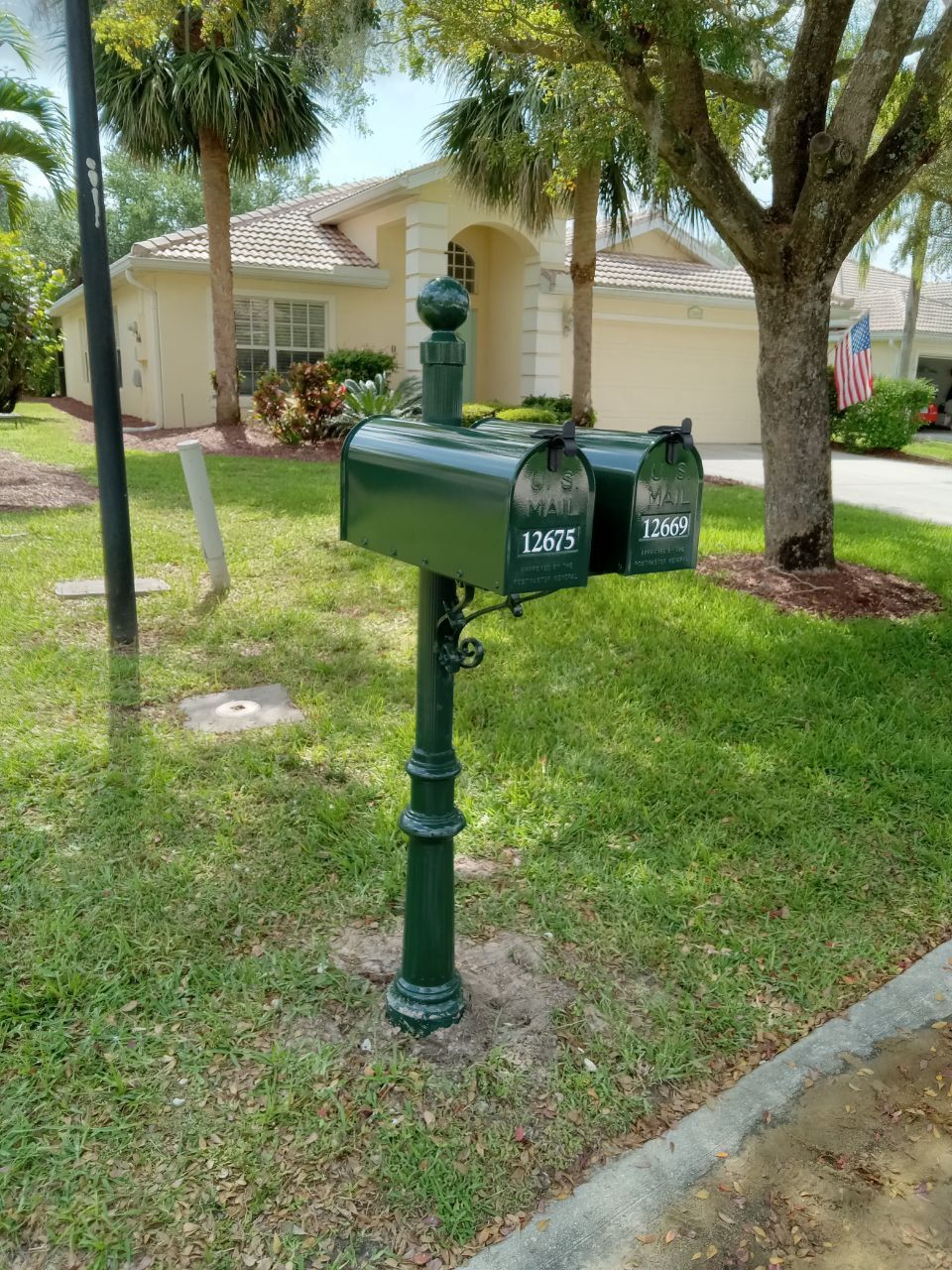 A green mailbox with two mailboxes in front of a house