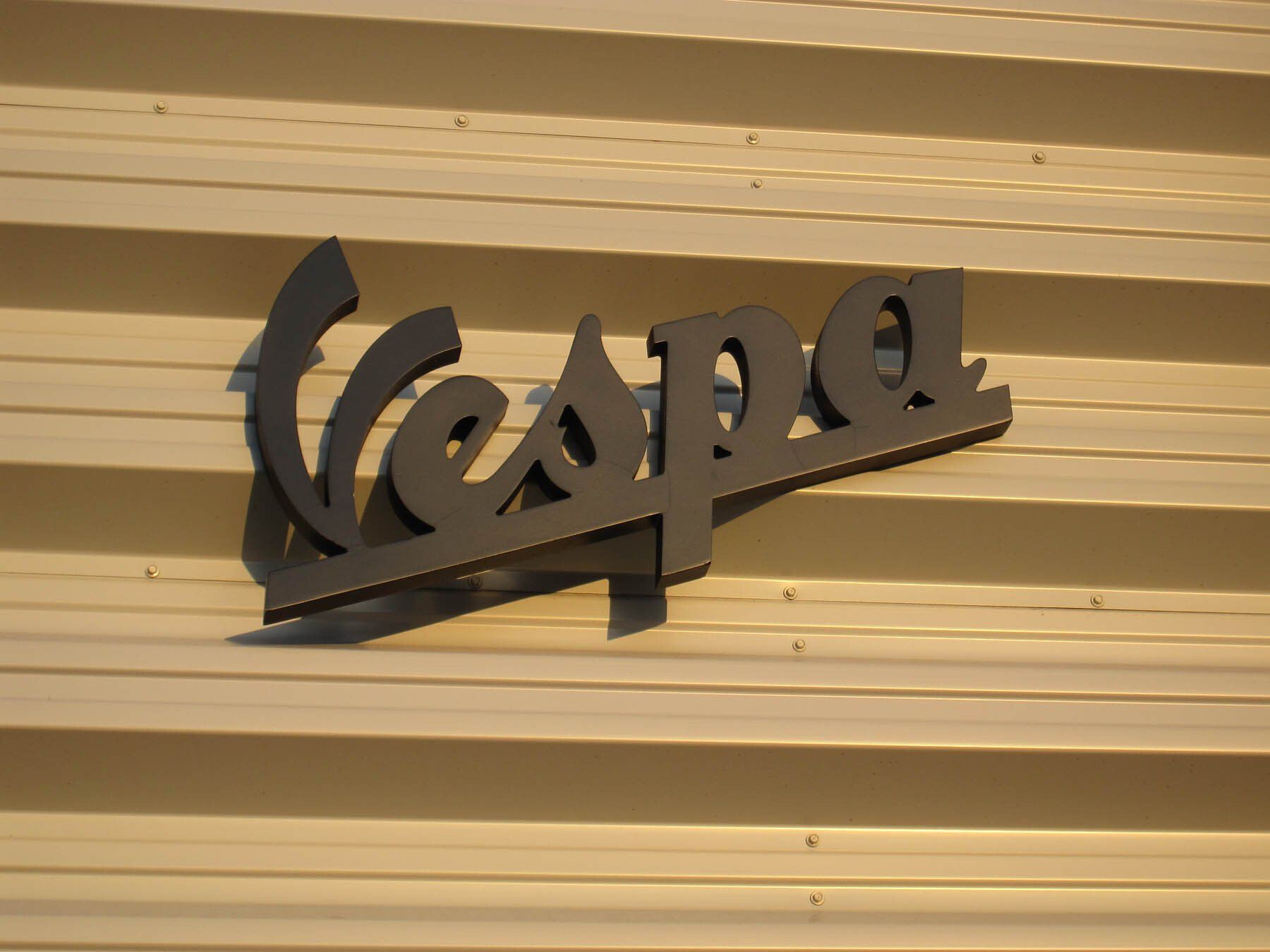 The word vespa is on a white wall