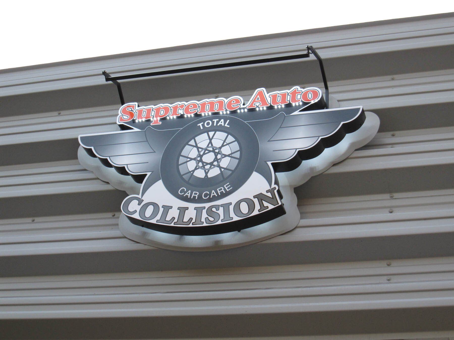 A sign on the side of a building that says supreme auto collision
