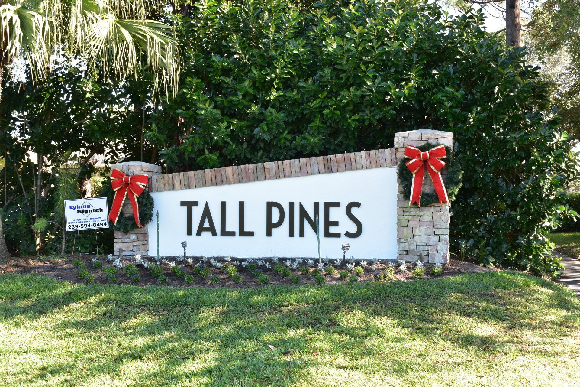 A tall pines sign with red bows on it