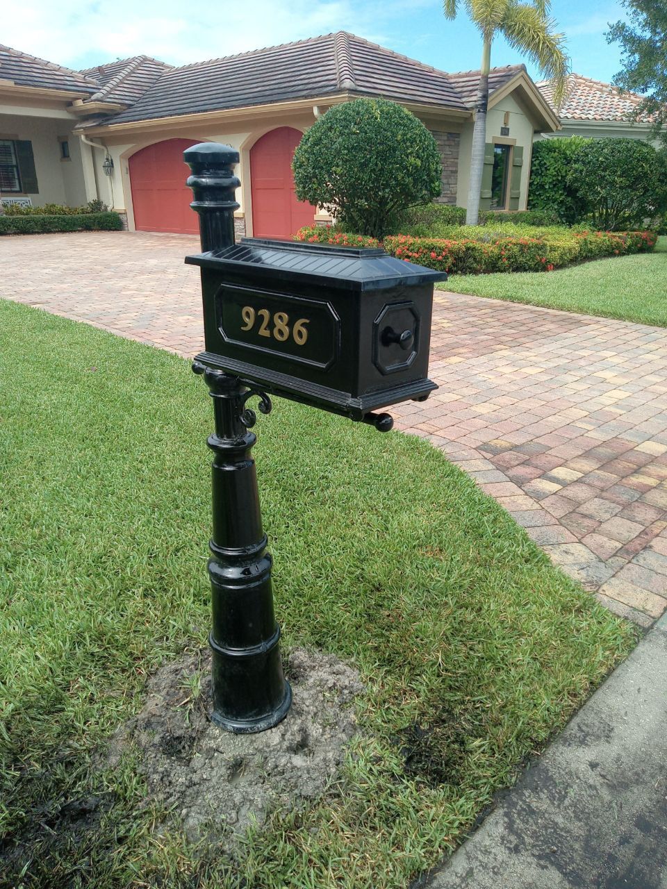 A black mailbox with the address 9286 is in front of a house.