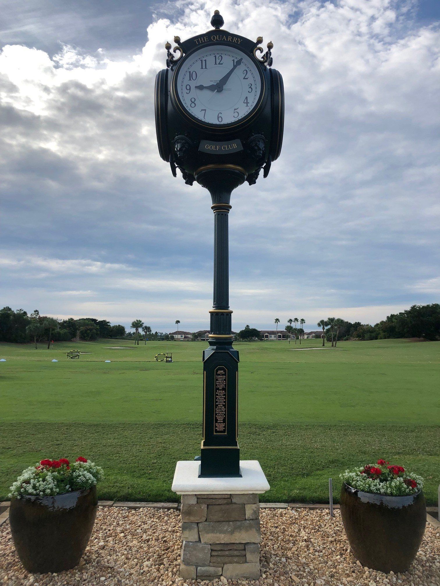 A large clock stands in the middle of a grassy field.
