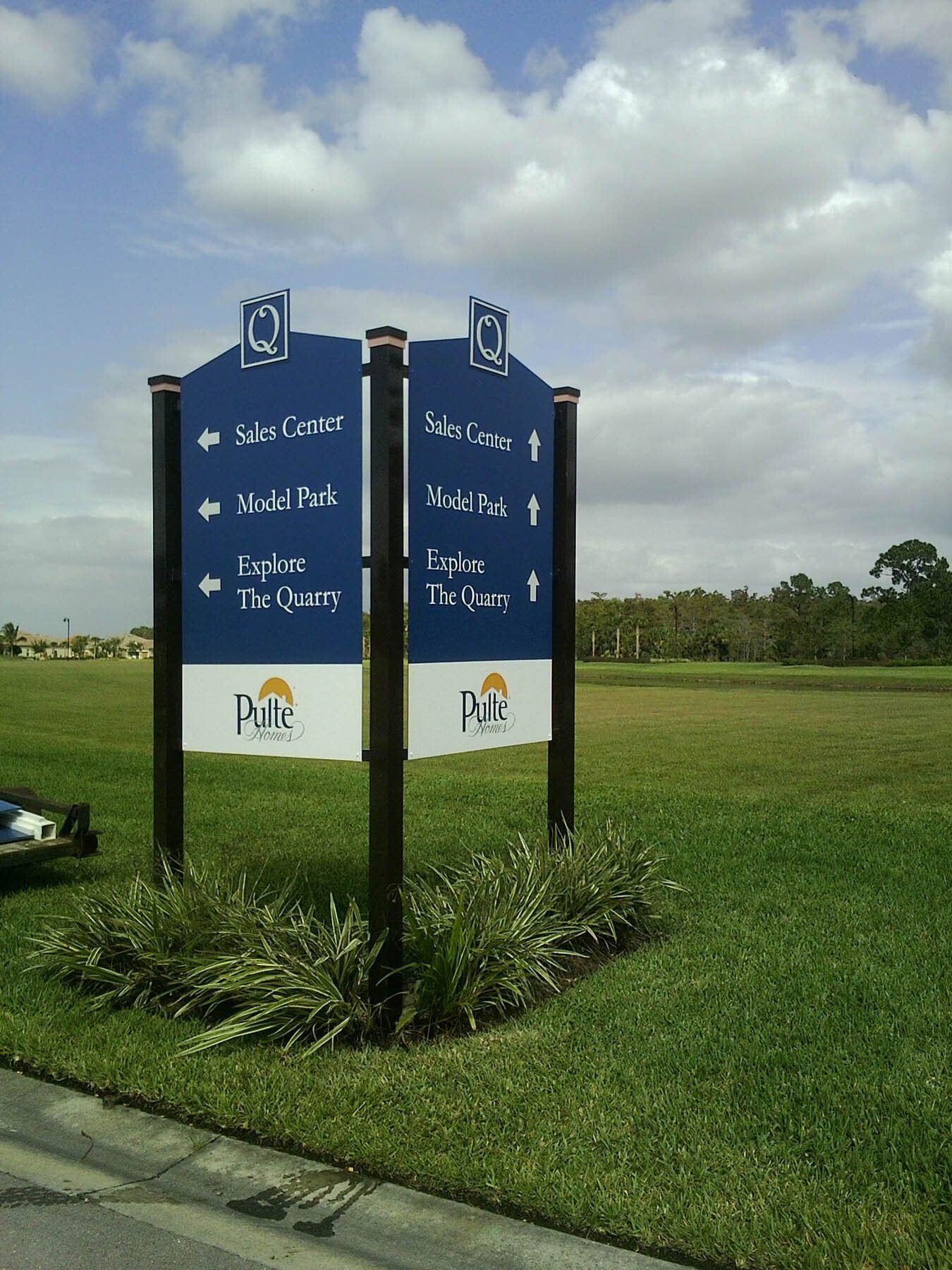 A couple of signs in a grassy field pointing in different directions