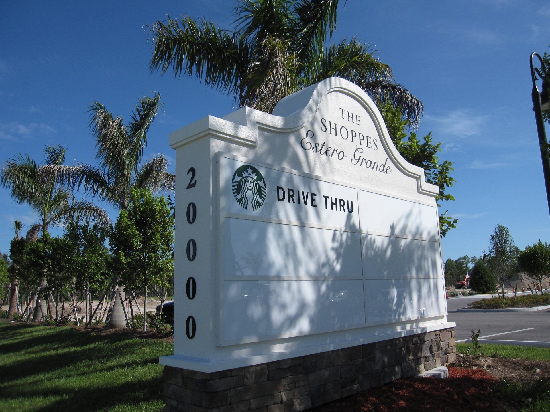 A white sign that says the shopper center grand