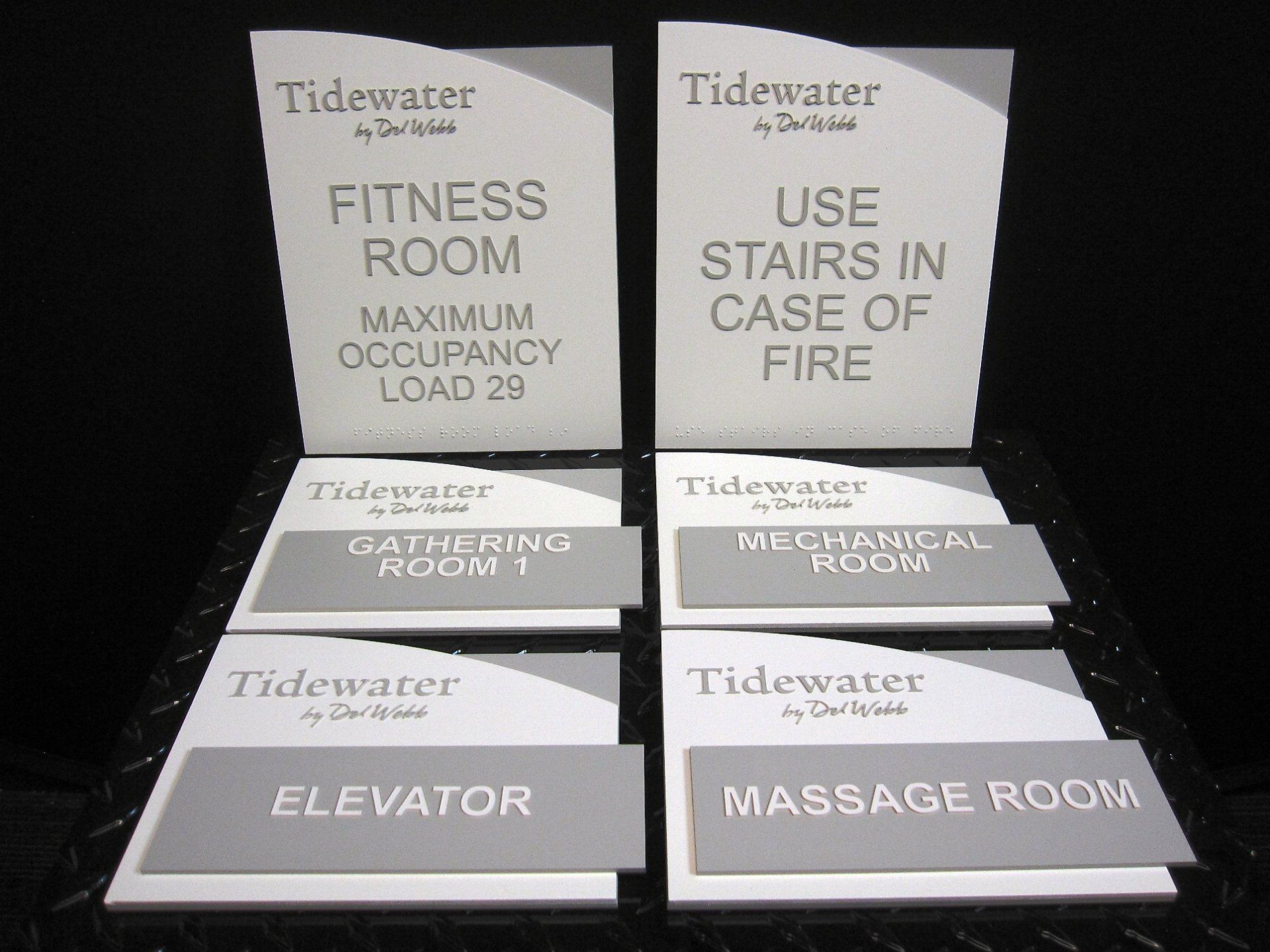 A set of signs that say tidewater fitness room and use stairs in case of fire