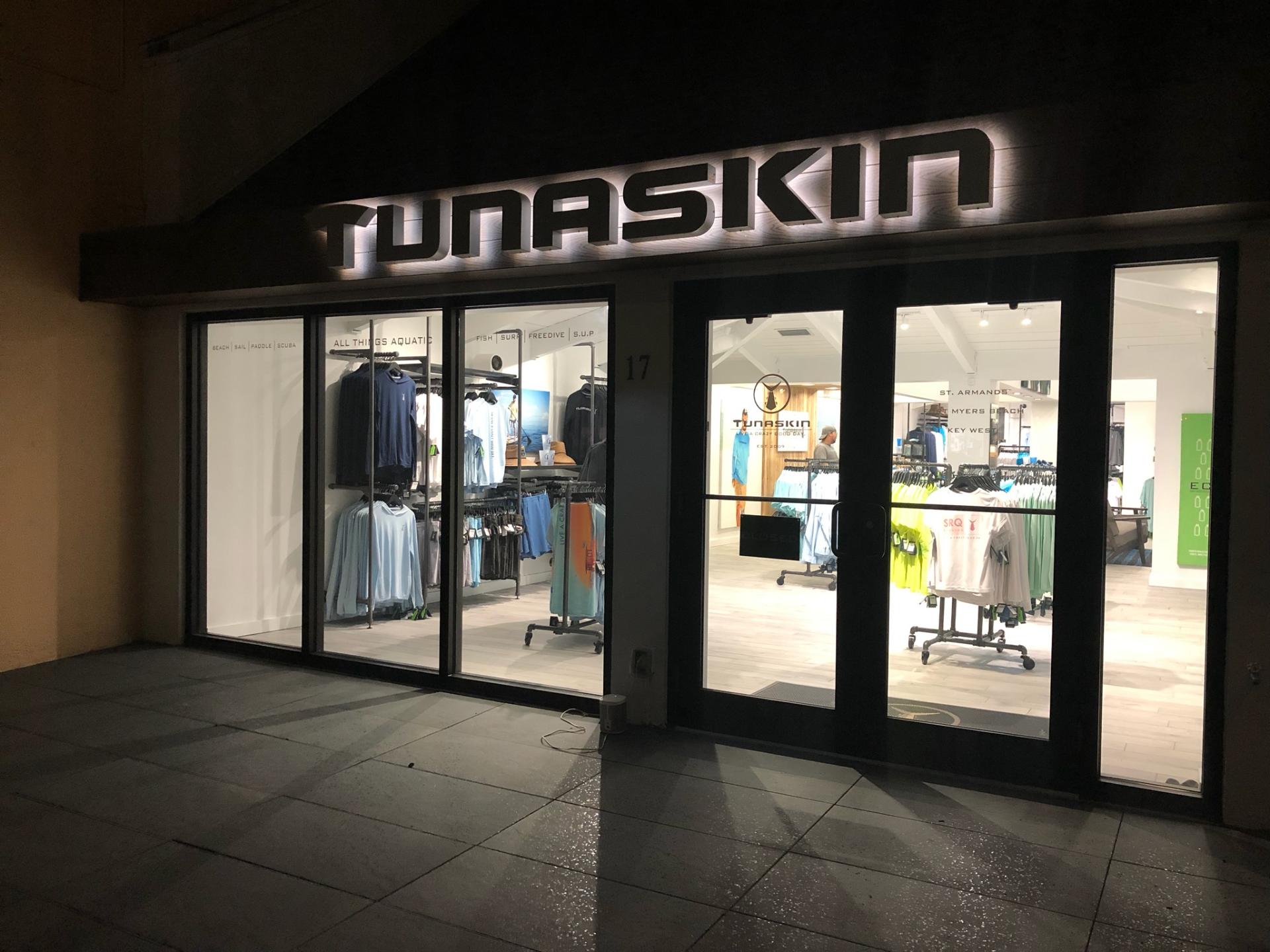 A tunaskin store is lit up at night.