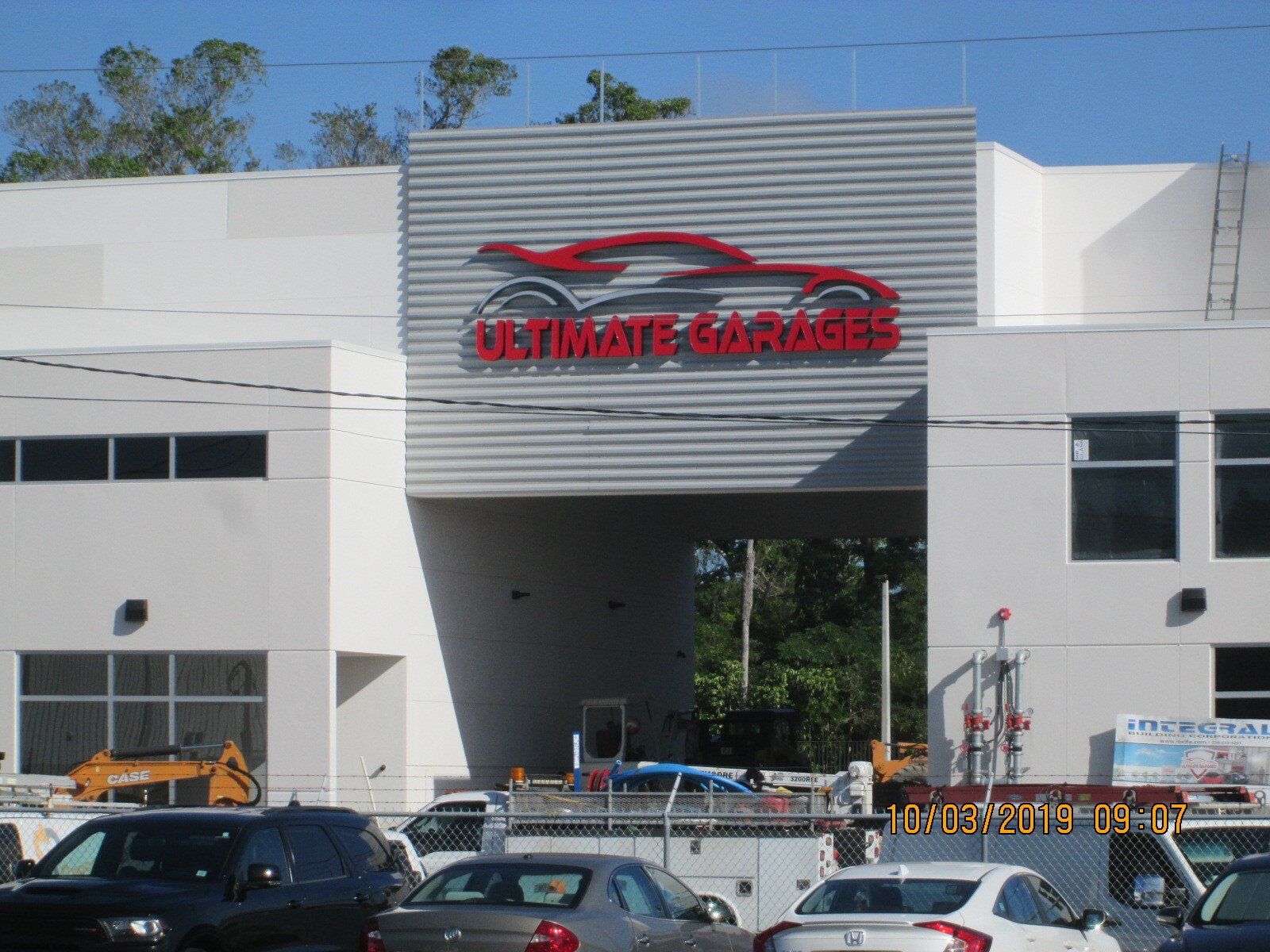 A white building with a red sign that says ultimate garages
