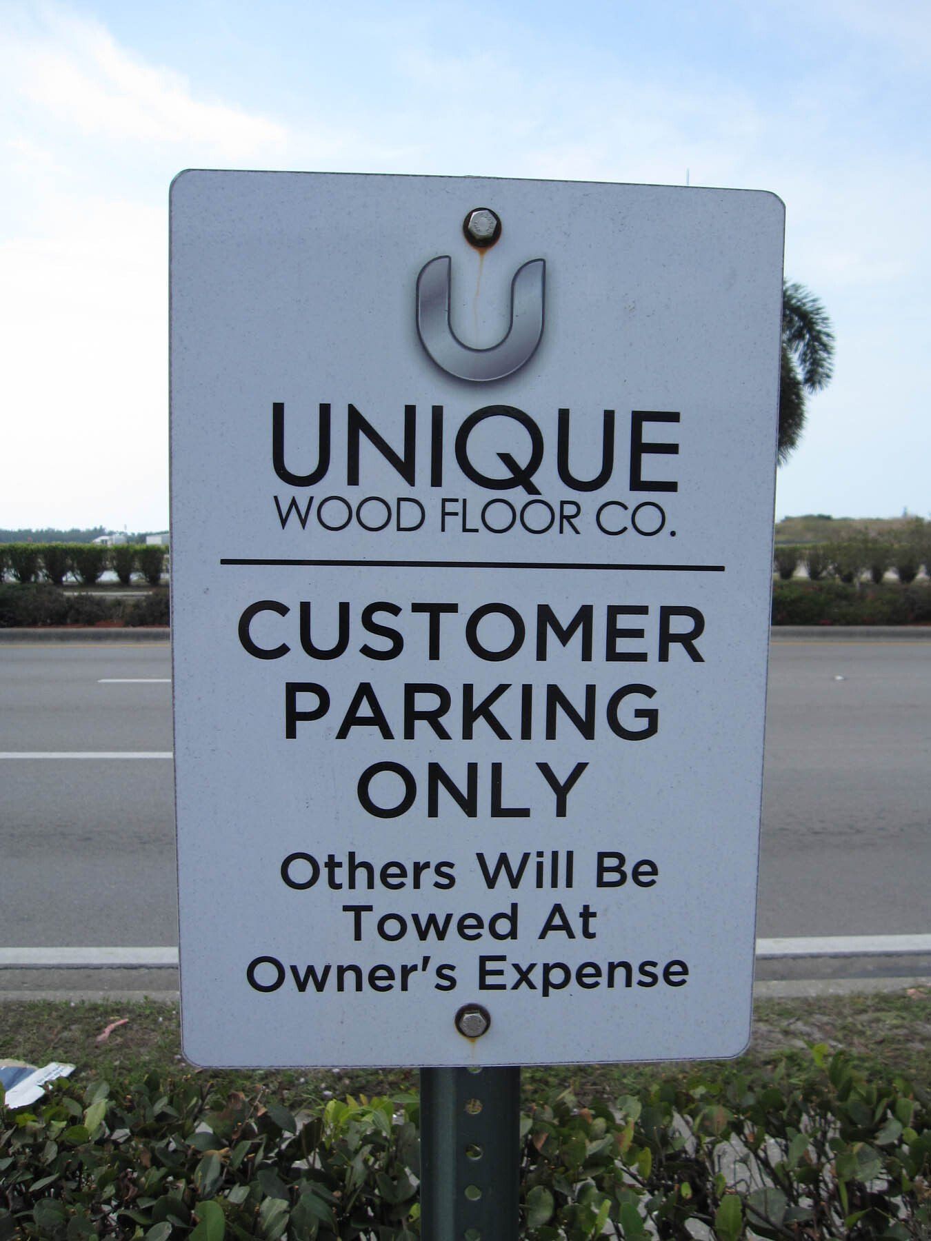 A sign that says unique wood floor co. customer parking only