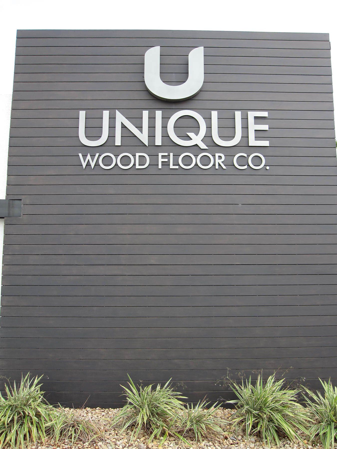 A large black sign for unique wood floor co.