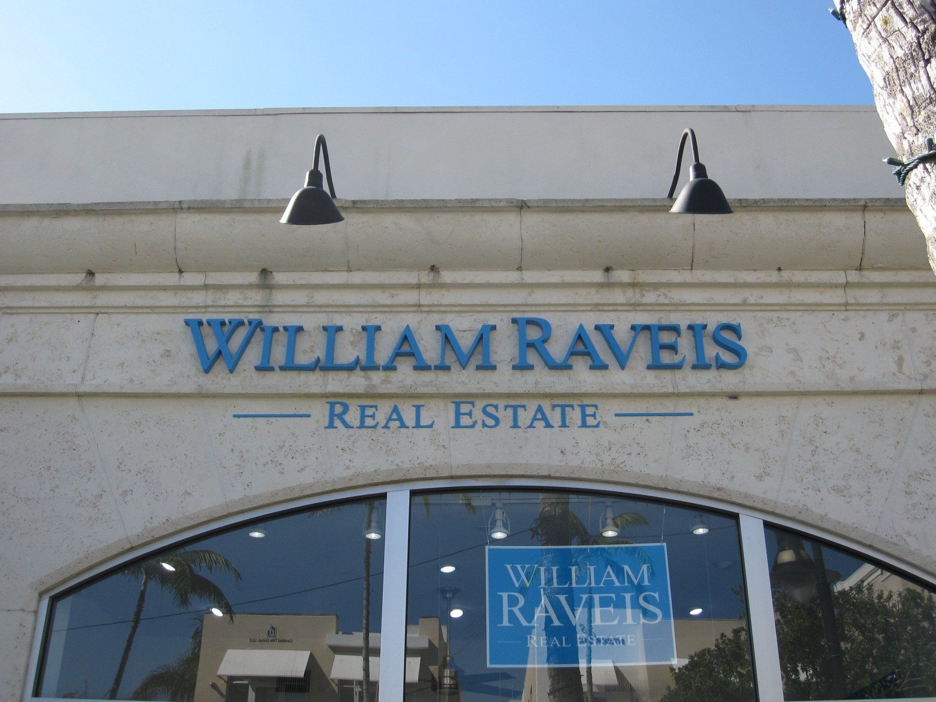 A sign for william raveis real estate hangs above a window