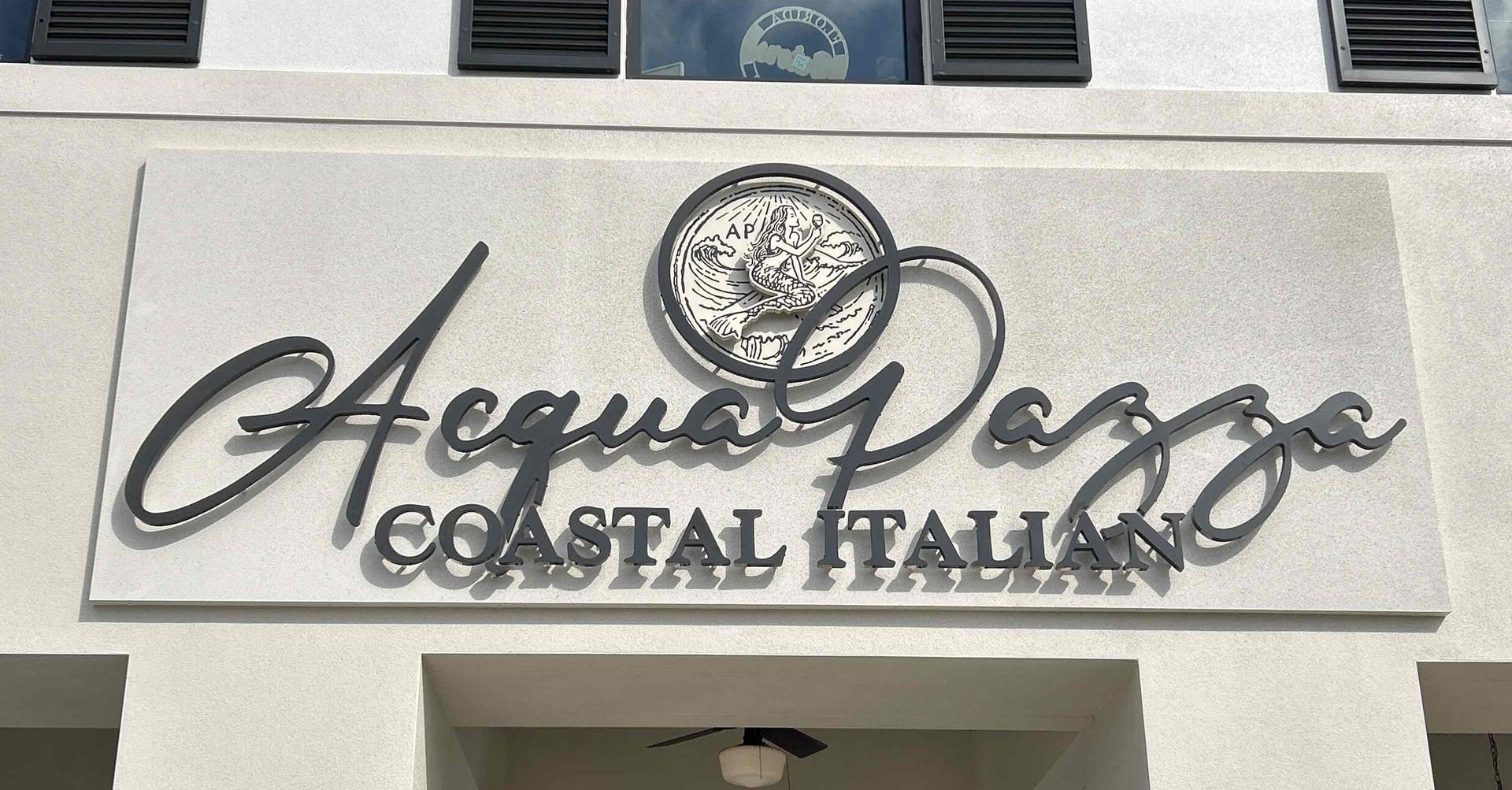A sign that says acqua pazza coastal italian on it