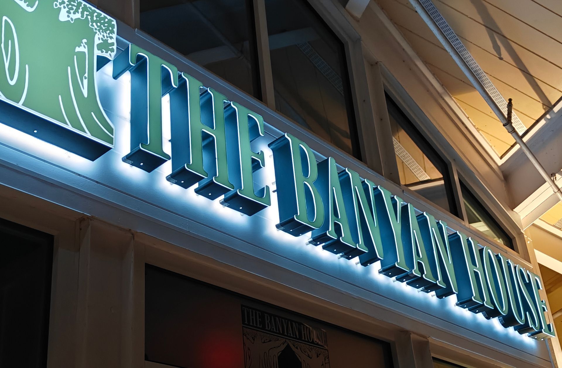 A sign for the hawaiian house is lit up at night