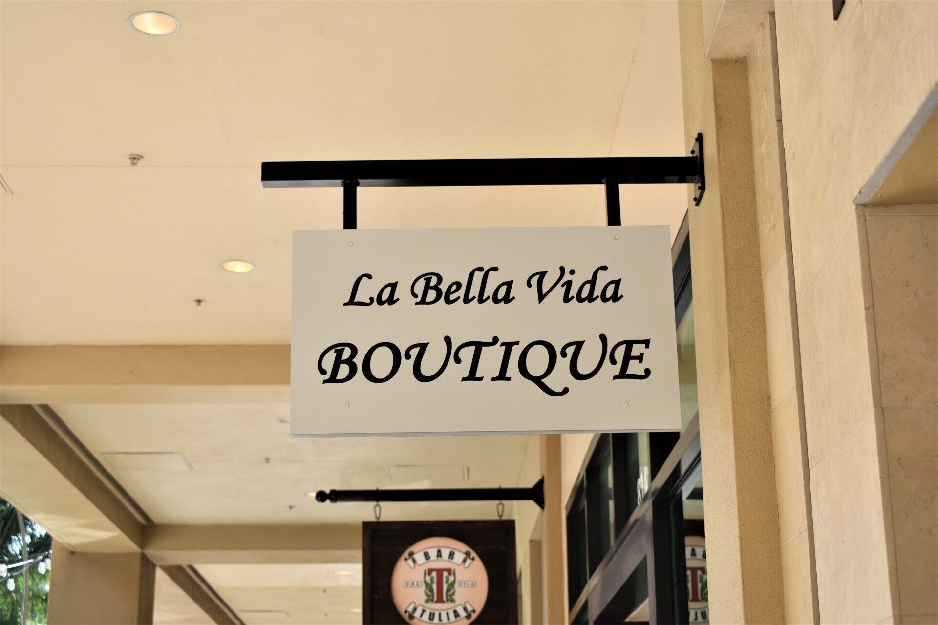 A sign for la bella vida boutique hangs from the side of a building