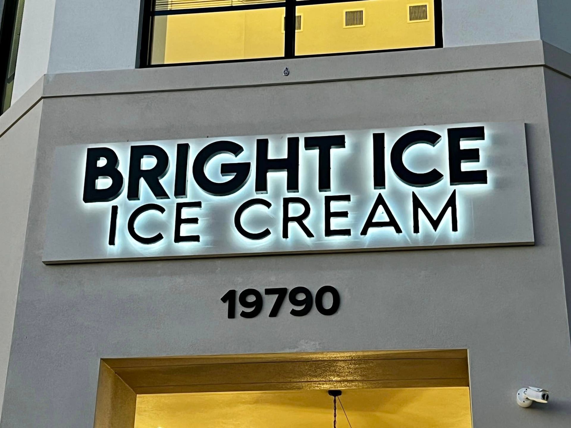 A sign for bright ice ice cream is lit up at night