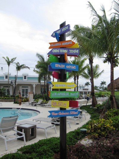 A colorful sign pointing in different directions in front of a pool