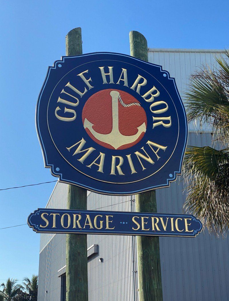 A sign for the gulf harbor marina with an anchor on it