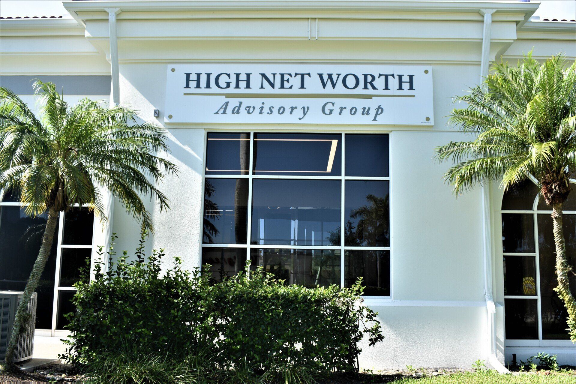 A white building with a sign that says high net worth advisory group