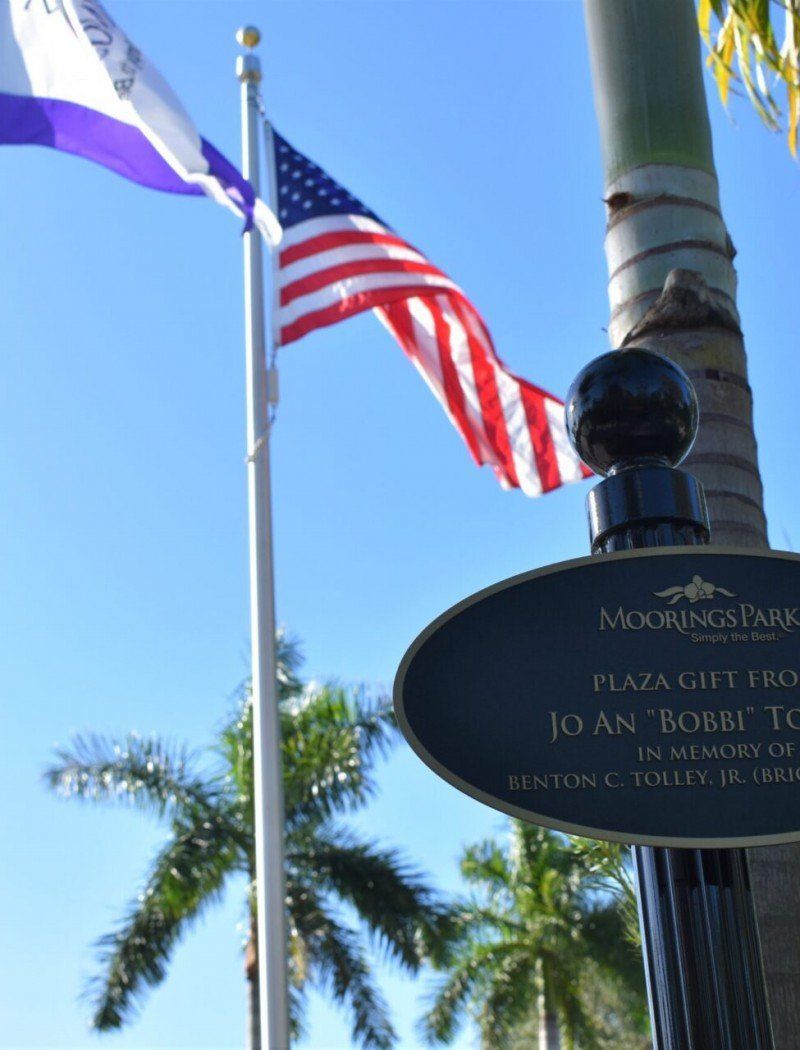 Two flags are flying in front of a sign that says moorhead park