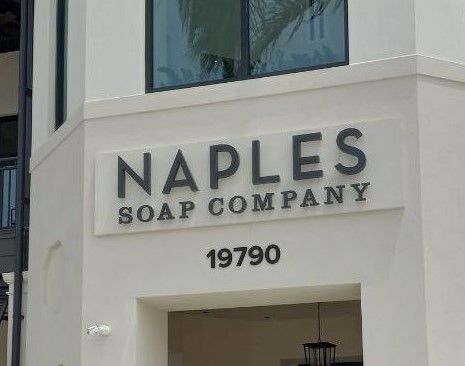 A white building with a sign that says naples soap company on it.