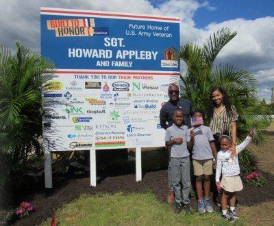 A group of people standing in front of a sign that says howard appleby and family