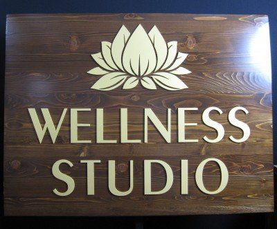A wooden sign for a wellness studio with a lotus flower on it