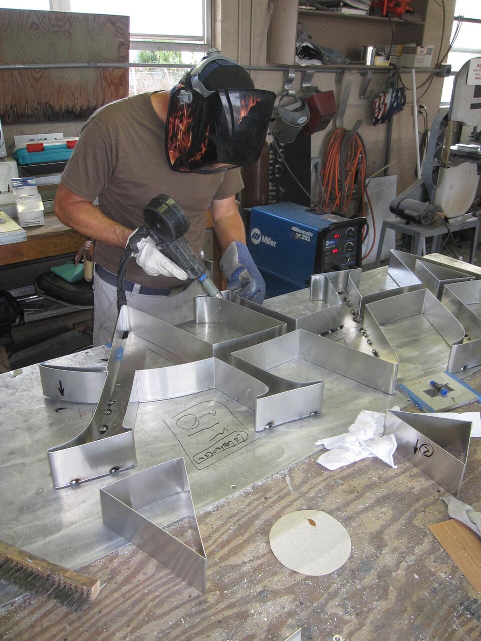 A man wearing a welding mask is working on a piece of metal.