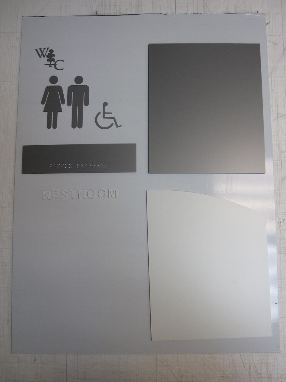 A sign for a restroom shows a man and a woman in a wheelchair