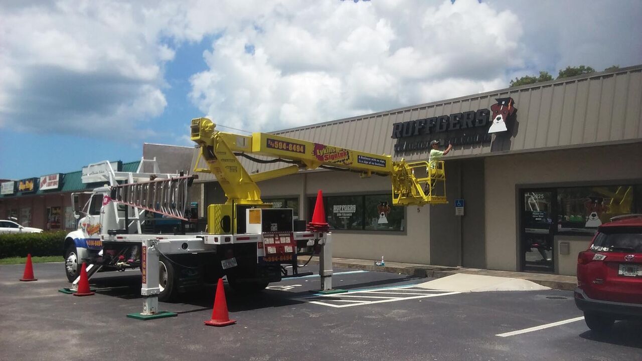 A truck with a crane attached to it is parked in front of a building.