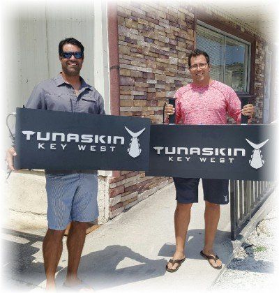 Two men holding signs that say tunaskin key west