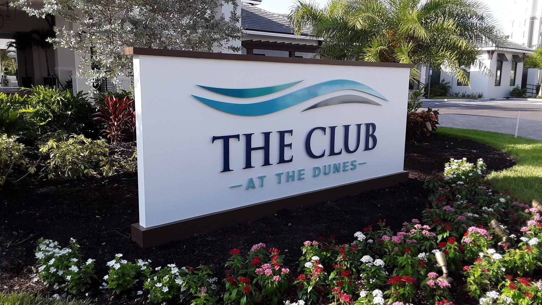 A sign for the club at the dunes is surrounded by flowers