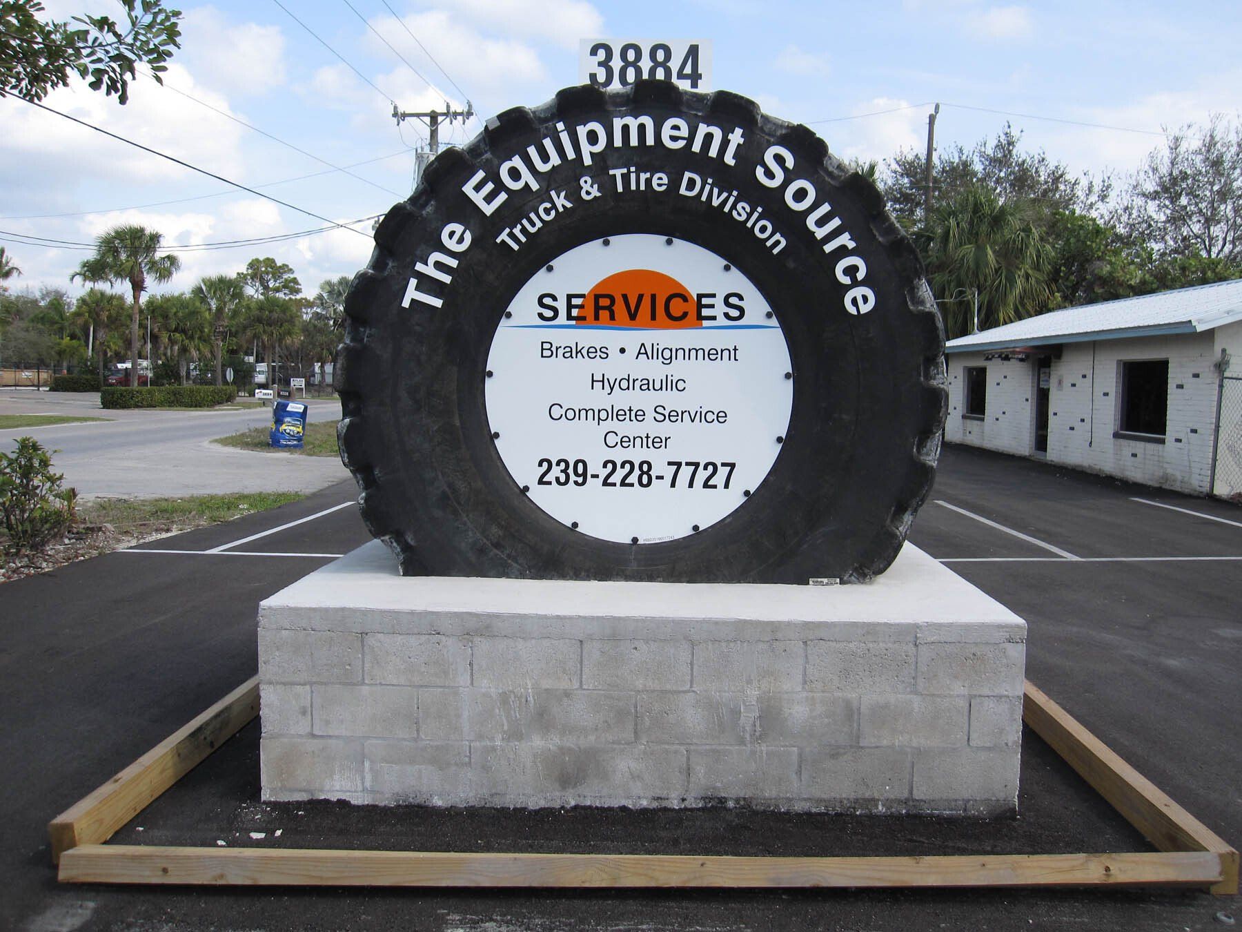 A large tire shaped sign for the equipment source