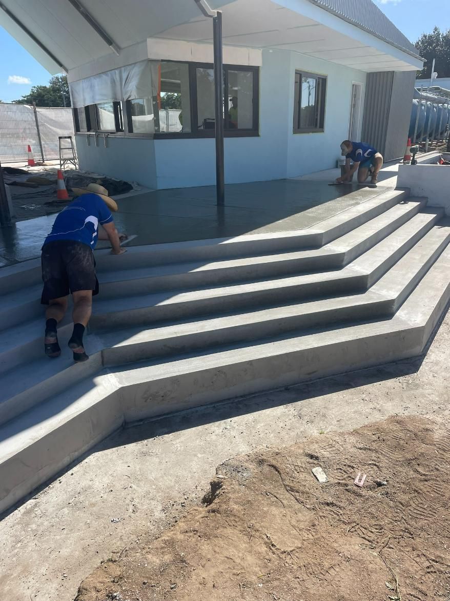A Man Is Working on A Set of Concrete Stairs in Front of A Building — Fallon Constructions NQ in Fredericksfield, QLD