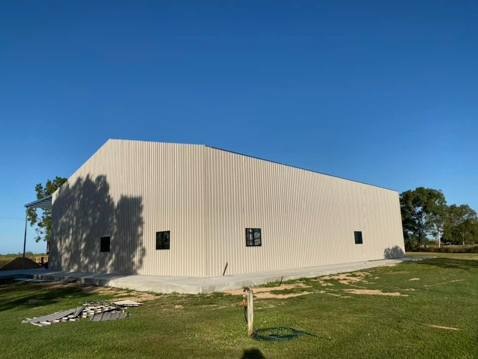 A Large White Building Is Sitting in The Middle of A Grassy Field — Fallon Constructions NQ in Fredericksfield, QLD