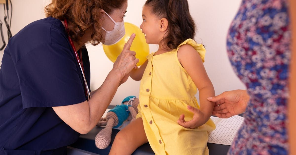 Pediatrician examining a smiling little girl while her parent watches